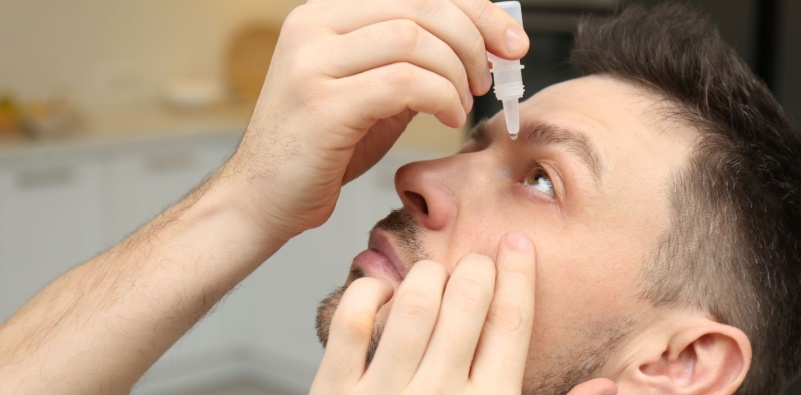 A man putting in eye drops
