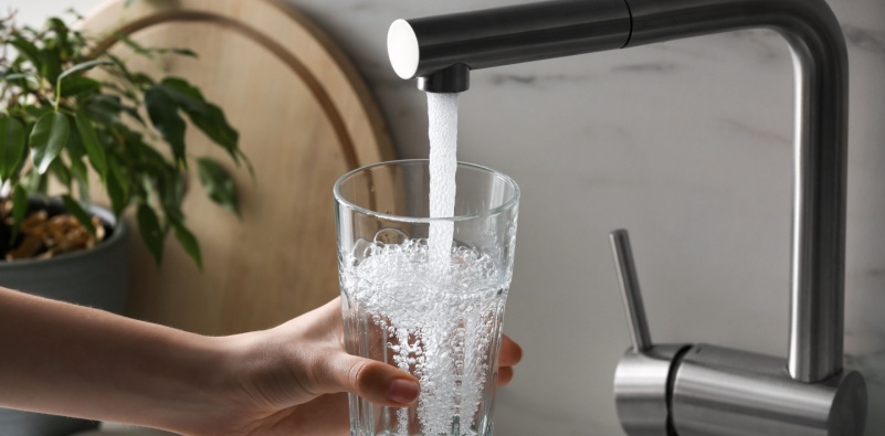 A woman filling a glass with water from a tap