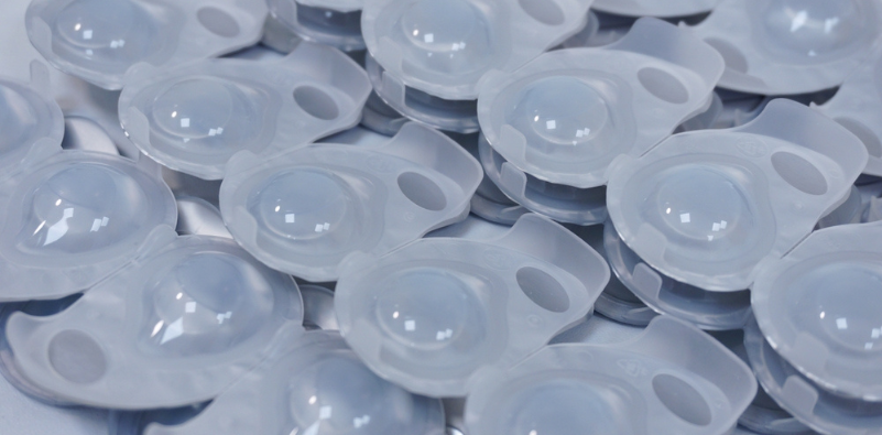 A close-up of several contact lens blister packs upside down, showing the contact lens through the plastic