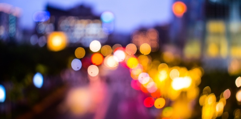 A visual example of vision with astigmatism, showing blurred and distorted lights on the road at night.