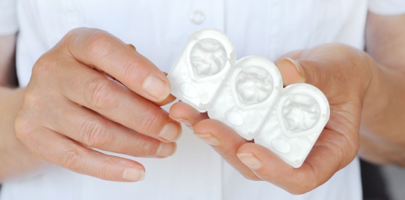 A close up of a person holding a blister pack of three contact lenses in their hand.