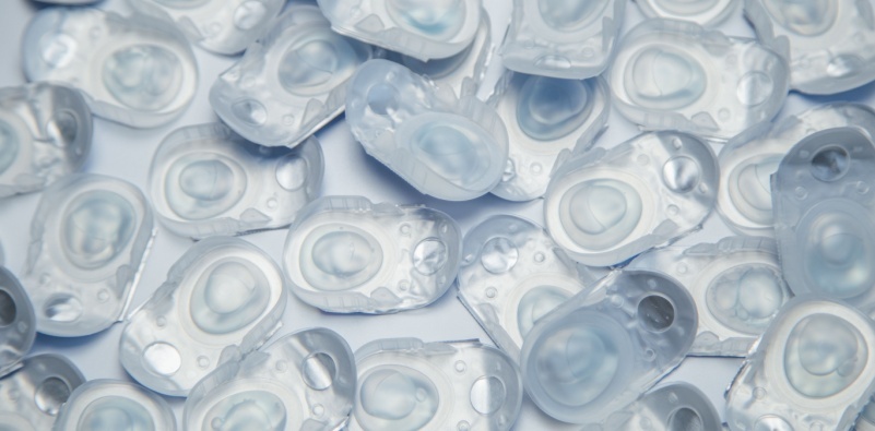 A close up of many daily disposable contact lenses blister packs on white surface.