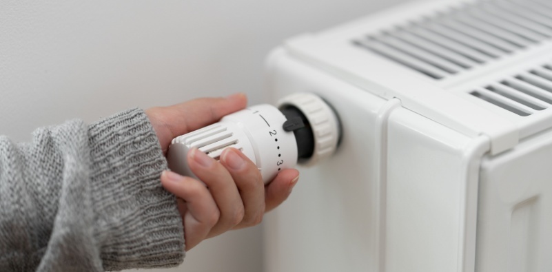 A person’s hand turning up the thermostat on a radiator.