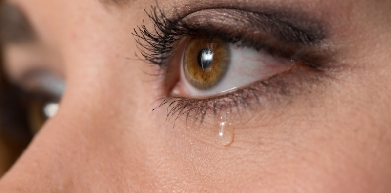 A close up of a woman’s face, with a tear drop running from her eye.