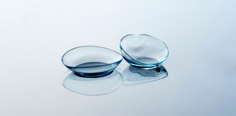 A pair of contact lenses on a neutral surface.