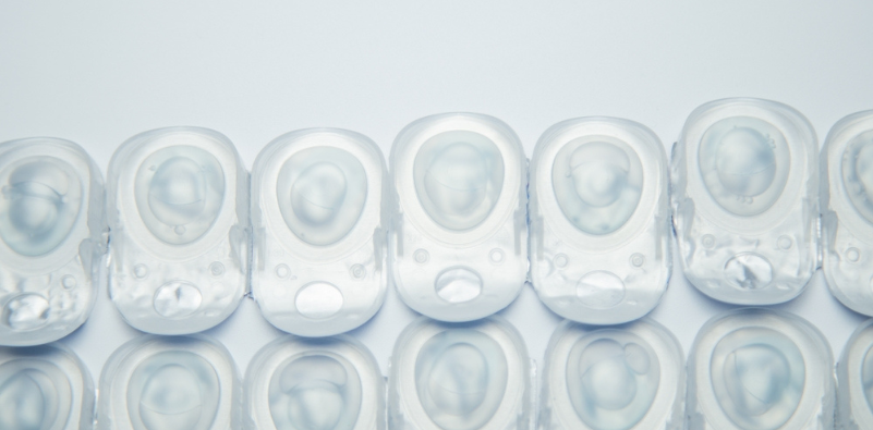 A strip of contact lens blister packets on top of a white, reflective surface.