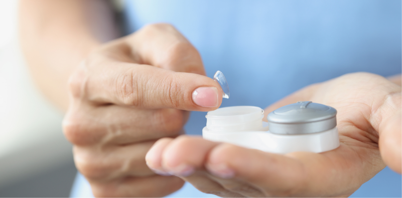 A close-up of a man’s hands placing a contact lens in a storage container.