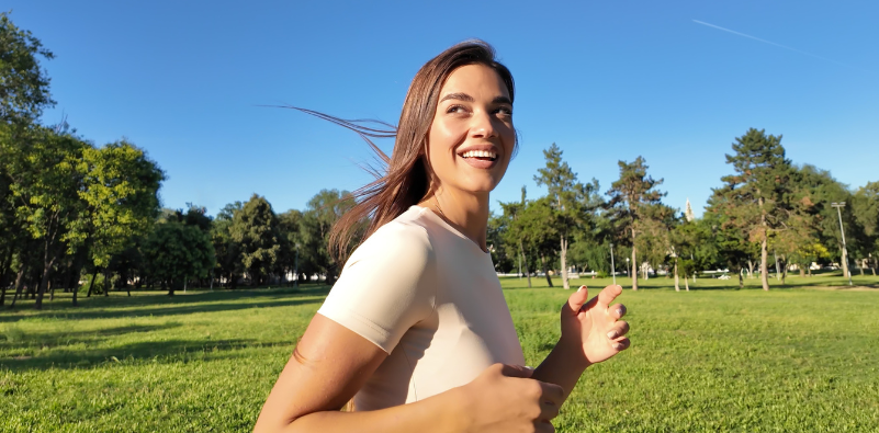 A young woman jogging in a sunny park