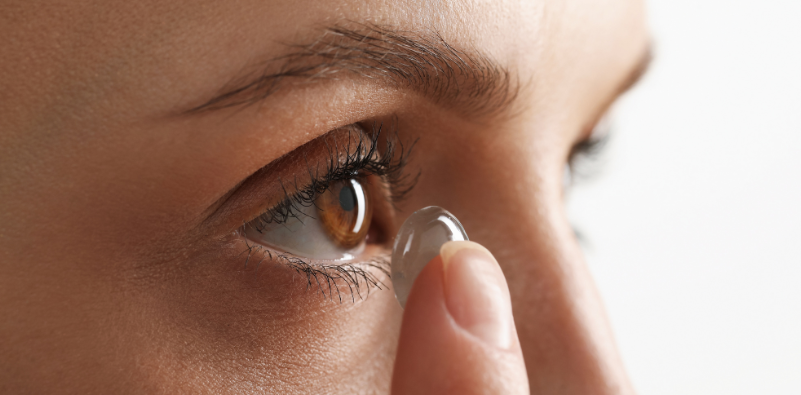 A close-up of a person inserting a contact lens.