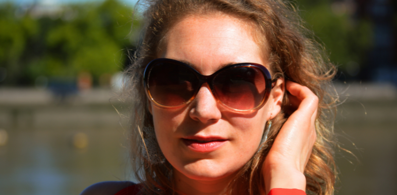 A woman wearing a pair of polarised sunglasses outdoors by a lake