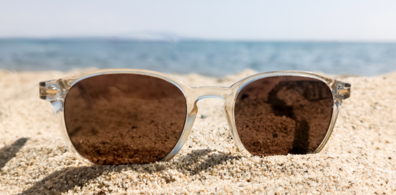 Polarised sunglasses resting on a sandy beach