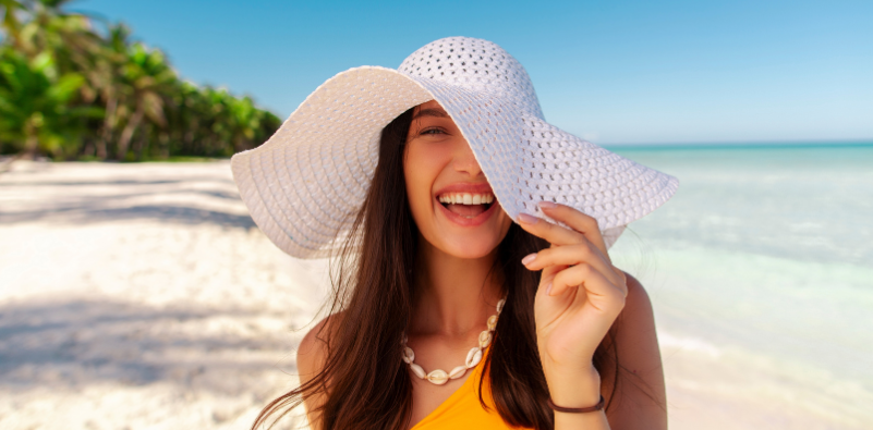 Smiling woman wearing a sun hat on the beach