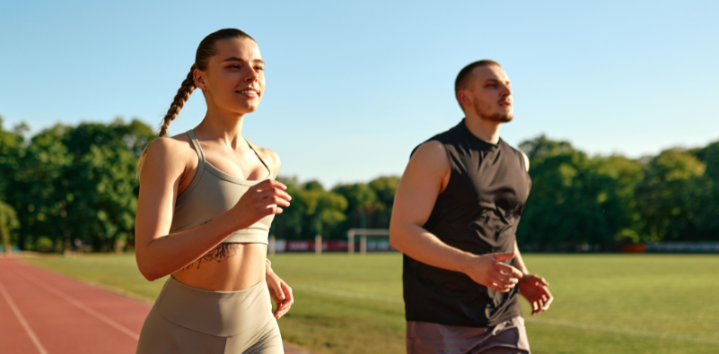 Two people jogging on an outdoor track.