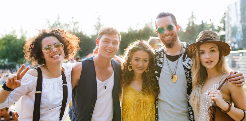 A group of friends smiling outdoors at a festival