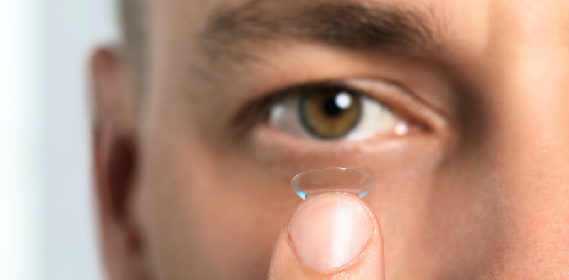 Man holding a soft contact lens on his fingertip before application